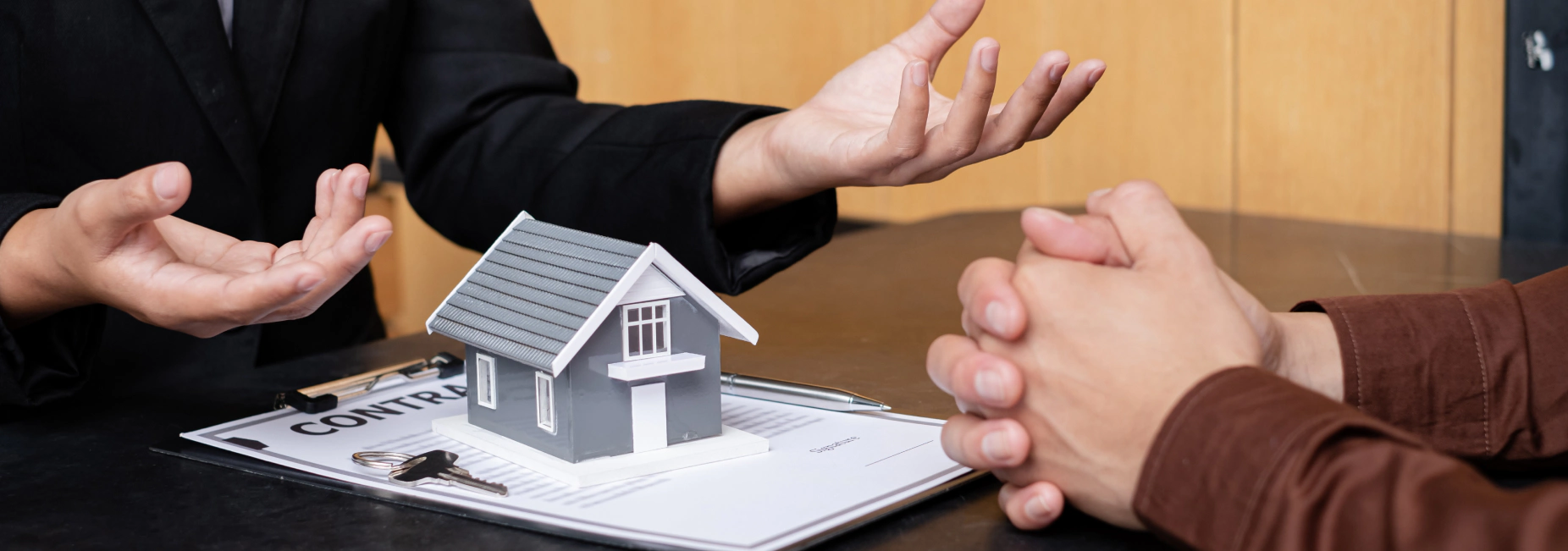 A real estate agent with a House model is talking to clients about buying home insurance. Home insurance concept dundalk md