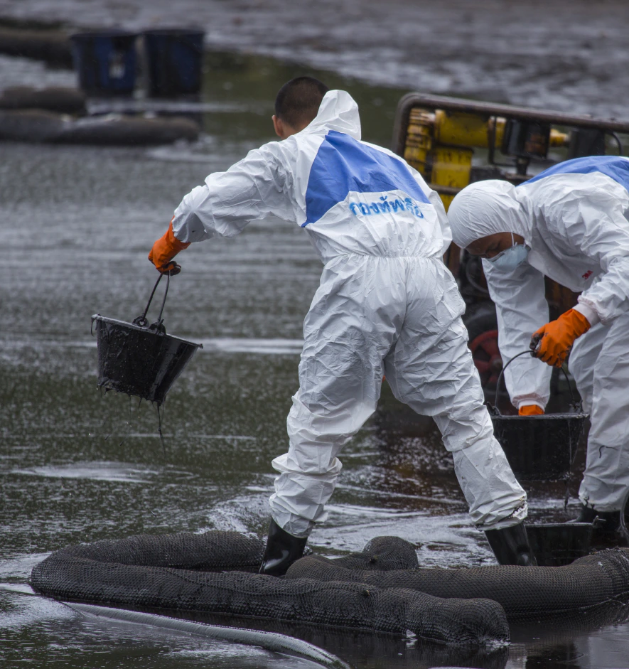 Workers wearing biohazard suits scoop a pail full of spilled crude oil as cleaning operations dundalk md